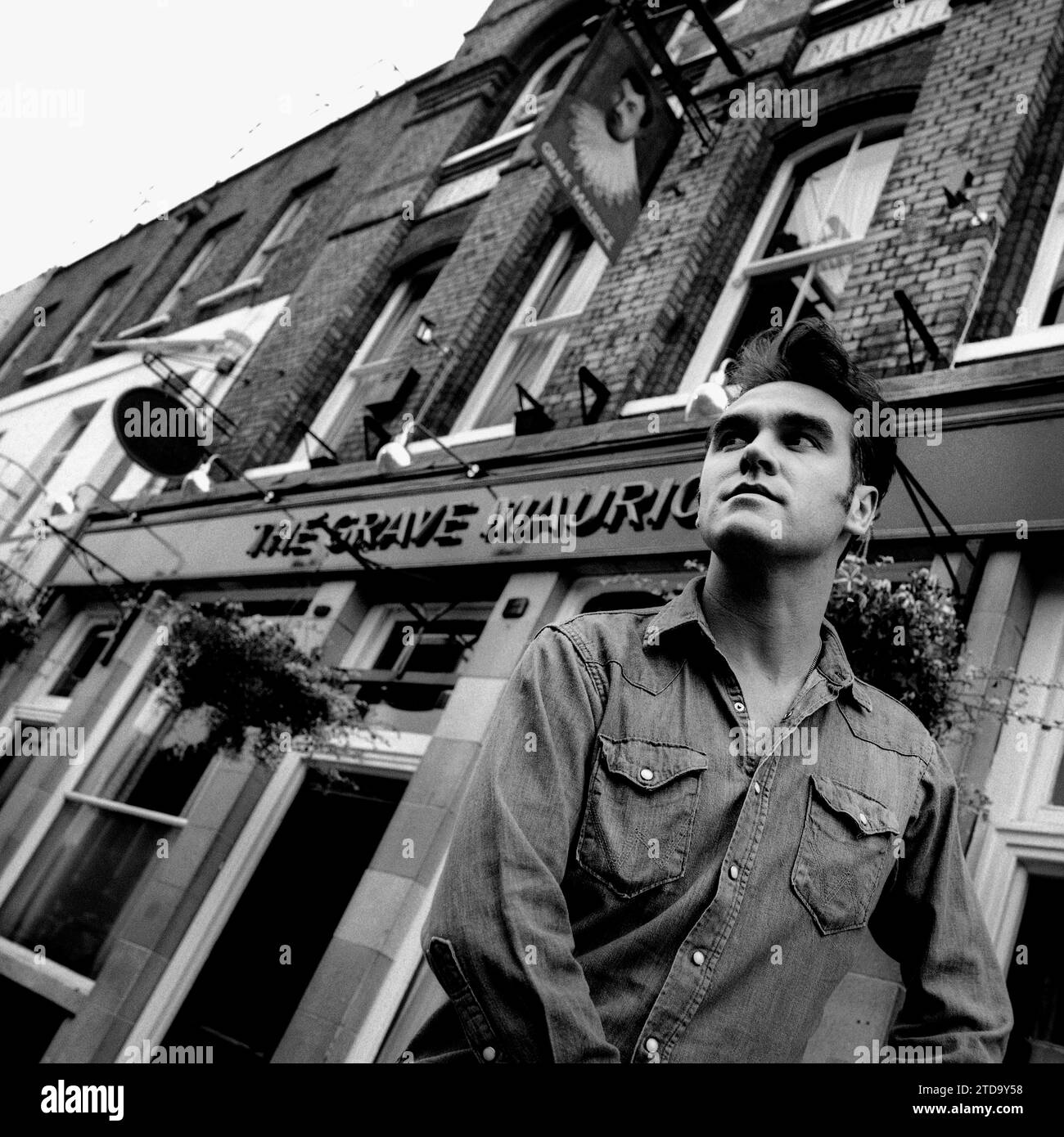 Puissant portrait noir et blanc de mi-plan de légendaire rockstar, chanteur / compositeur Morrissey en chemise en denim. Tourné dans la rue devant le pub grave Maurice, Whitechapel dans l'East End de Londres pour promouvoir son single Sunny pour Parlophone Records 1995. Banque D'Images