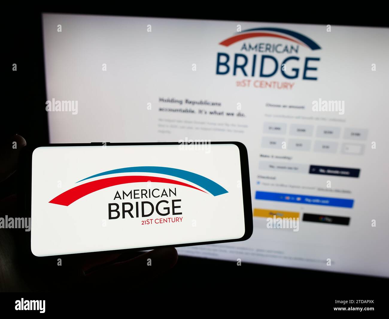 Personne tenant le smartphone avec le logo de libéral Super PAC American Bridge 21st Century en face du site Web. Concentrez-vous sur l'affichage du téléphone. Banque D'Images