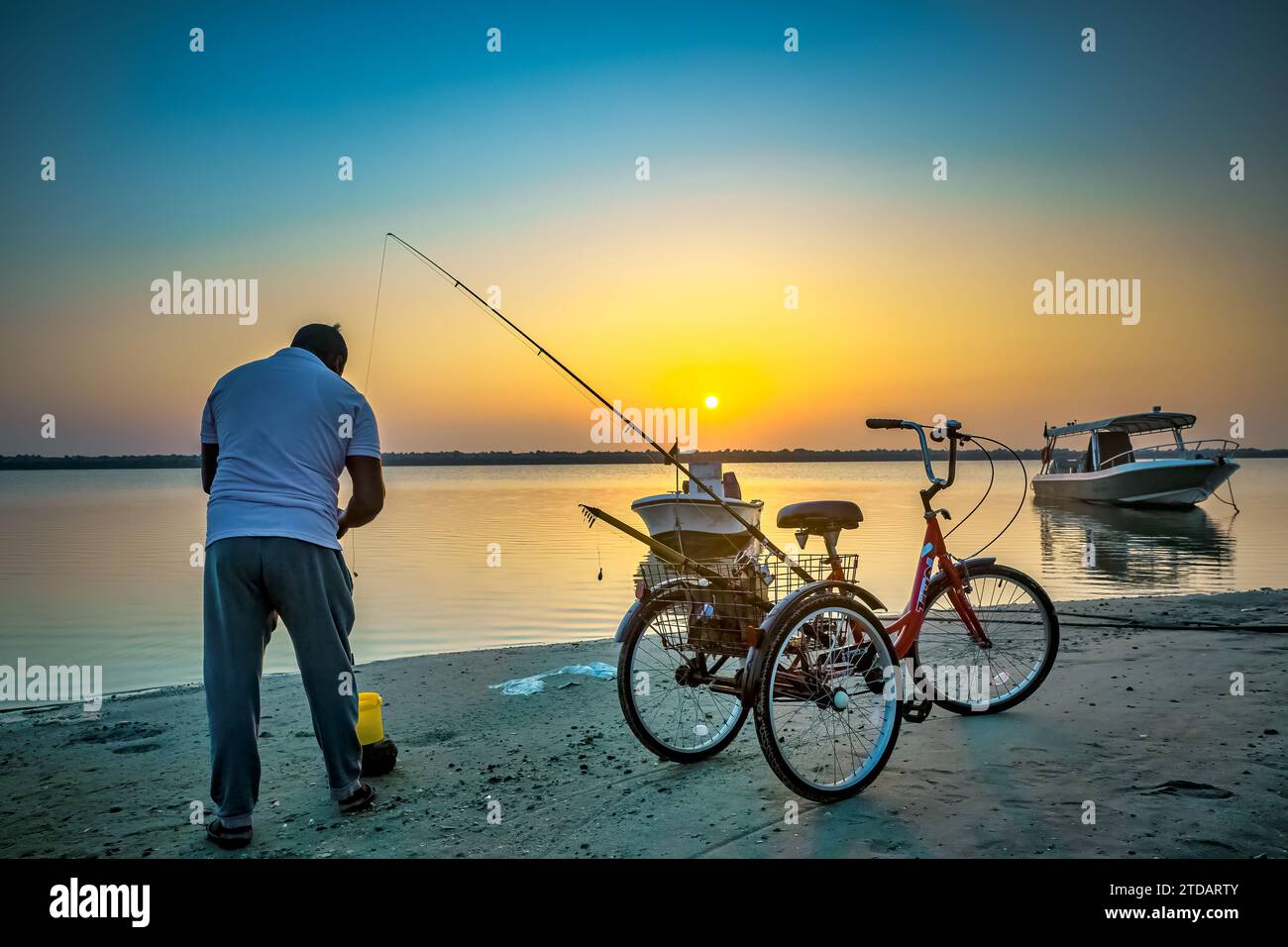 Coastal Serenity : pêche à la ligne à Dammam Corniche, Arabie Saoudite avec Bicycle Companion. Banque D'Images