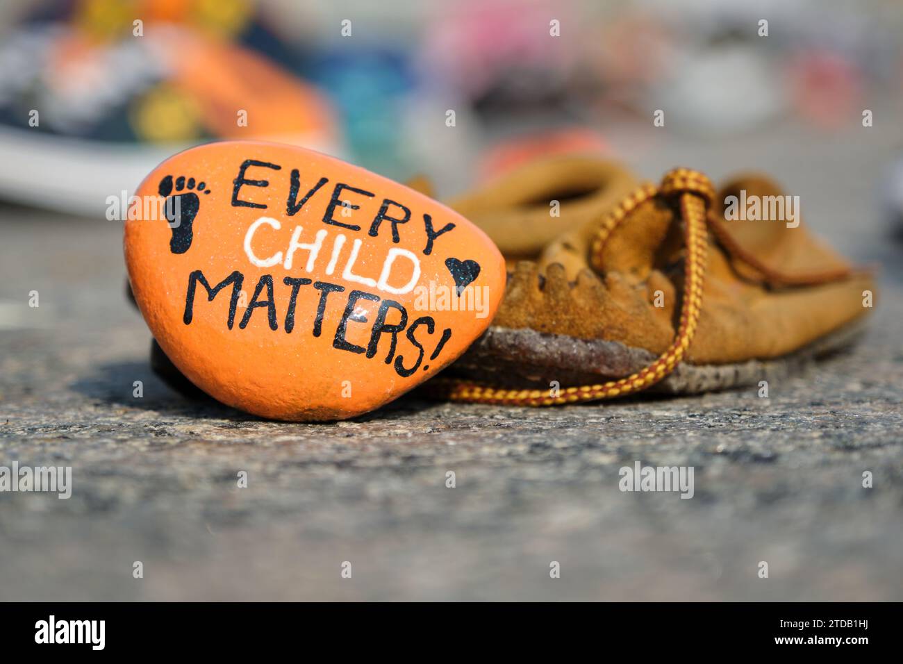 Mémorial aux enfants autochtones qui demeurent dans les pensionnats du Canada. Mocassin pour enfants et roche orange peinte en mémoire, Ottawa Banque D'Images