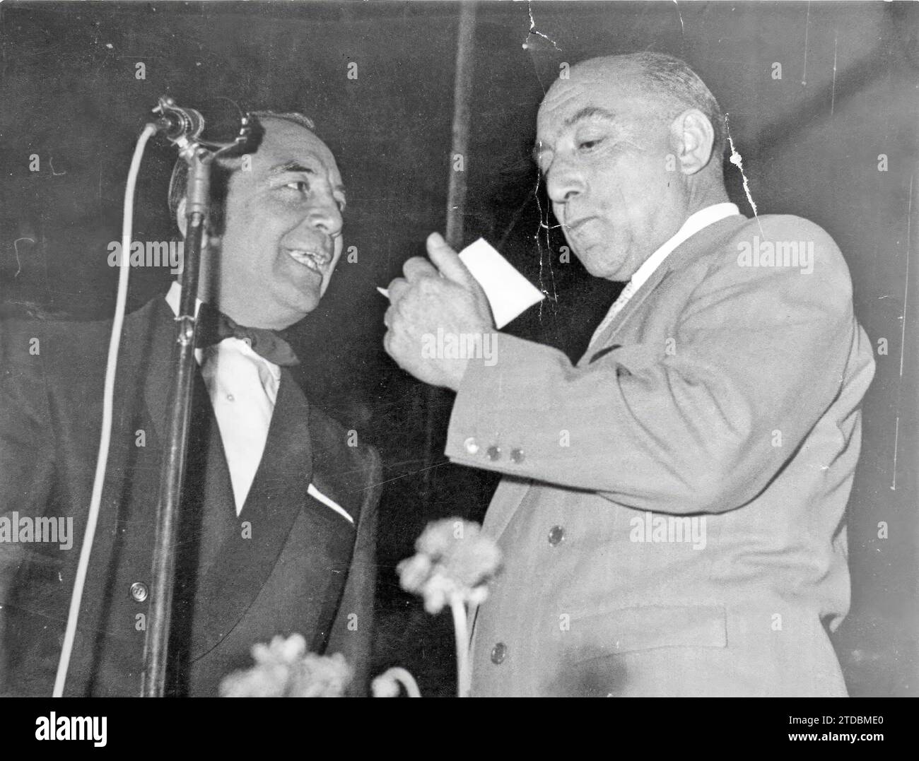 Madrid, juillet 1958. Don Enrique Serrano Borruel, à droite, plombier de Madrid, reçoit des mains de M. Boby Deglané, heureux créateur et animateur des concours radiophoniques les plus populaires, le chèque de cent mille pesetas qu'il a reçu pour avoir remporté le concours. 'Où sera l'avion ?' Pourquoi as-tu dit Orense ? l'annonceur demanda. "Parce que ma femme vient de là, et si je ne dis pas Orense et que l'avion est à Orense...". Crédit : Album / Archivo ABC / Teodoro Naranjo Domínguez Banque D'Images