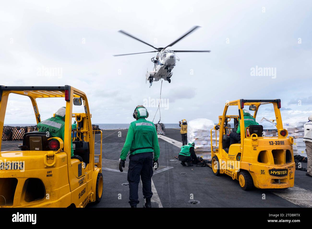 231209-N-TY704-1955 PHILIPPINE SEA (9 décembre 2023) des marins déplacent de la cargaison pendant qu'un hélicoptère EC225LP d'Eurocopter se prépare à déposer de la cargaison sur le pont d'envol du porte-avions USS Carl Vinson (CVN 70) de la classe Nimitz lors d'un réapprovisionnement vertical. Vinson, navire amiral du Carrier Strike Group ONE, est déployé dans la zone d'opérations de la 7e flotte américaine à l'appui d'un Indo-Pacifique libre et ouvert. (Photo de la marine américaine par Emily Claire Bennett, spécialiste des communications de masse de 2e classe) Banque D'Images