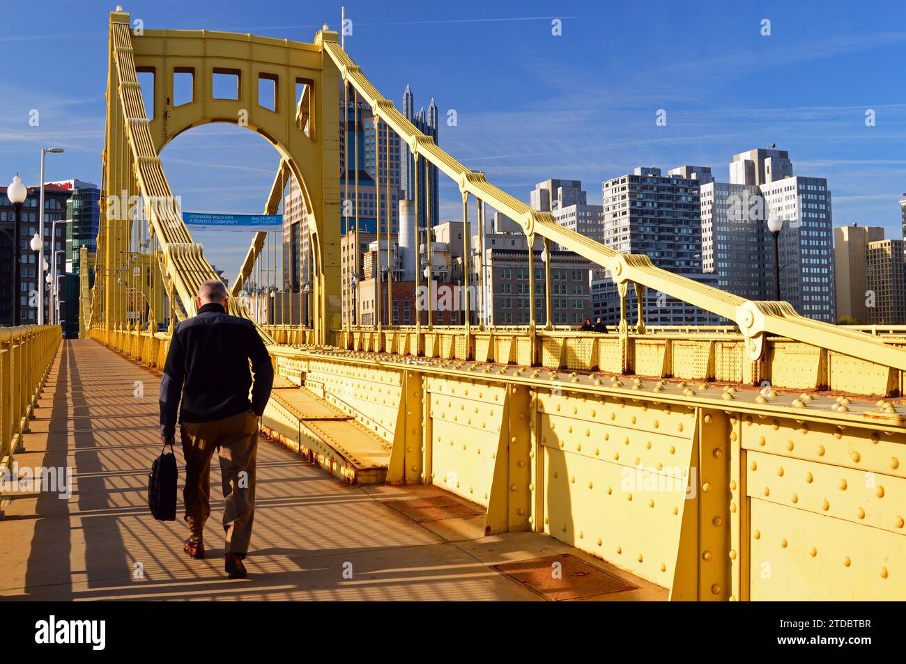 Un homme adulte se rend à son travail dans le centre-ville de Pittsburgh en Pennsylvanie en traversant le pont jaune Roberto Clemente par une journée ensoleillée Banque D'Images