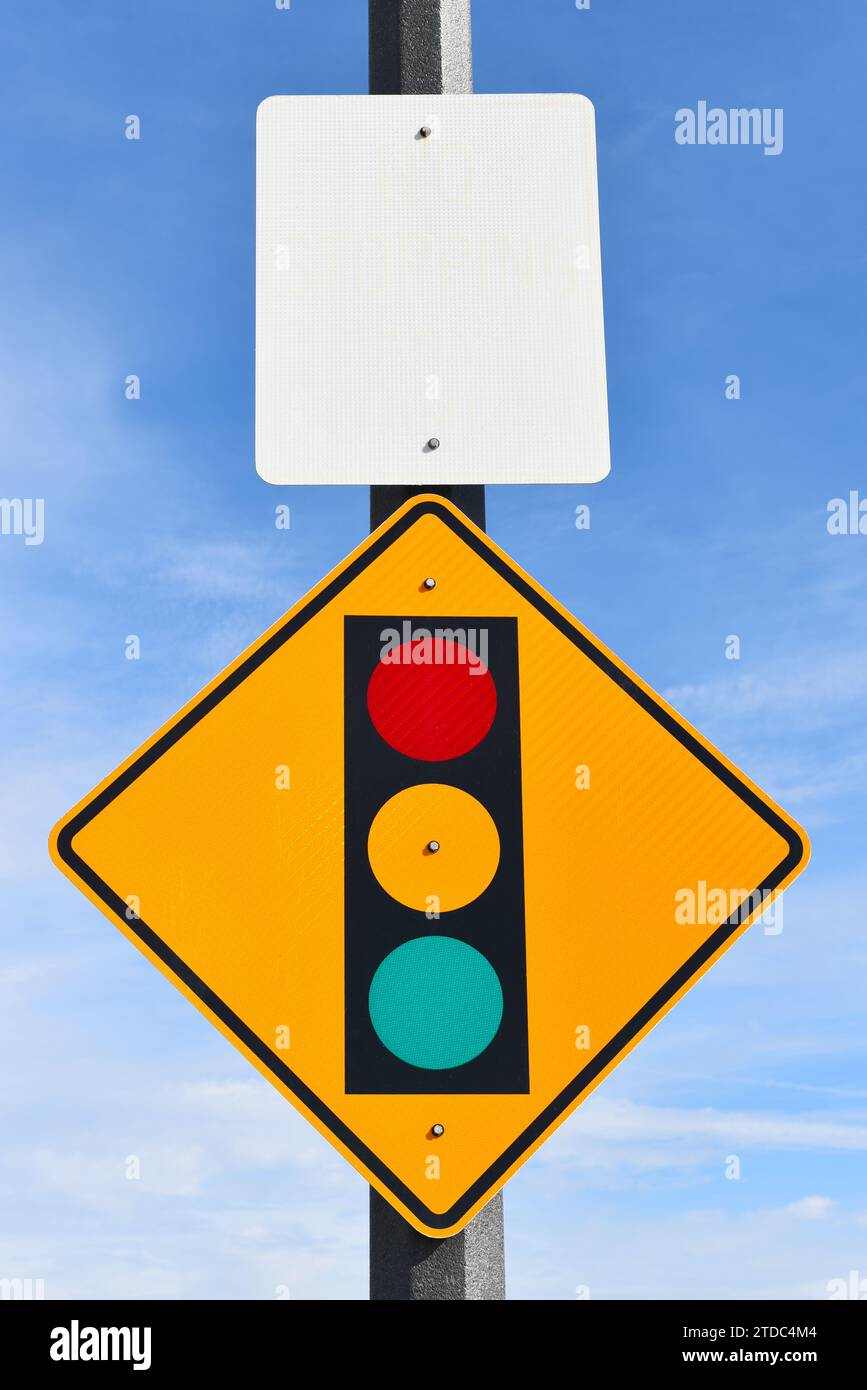 Signal d'arrêt avant le panneau d'avertissement sur le poteau avec un panneau blanc noir contre un ciel bleu rayé de nuages Banque D'Images