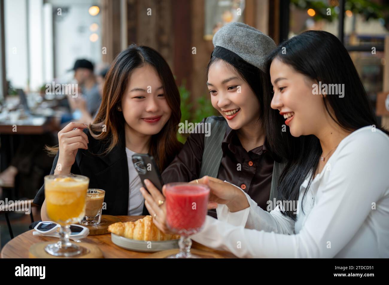 Groupe d'amies asiatiques joyeuses et attrayantes apprécient traîner dans un café ou un restaurant dans la ville ensemble, chit bavarder, regarder somet Banque D'Images