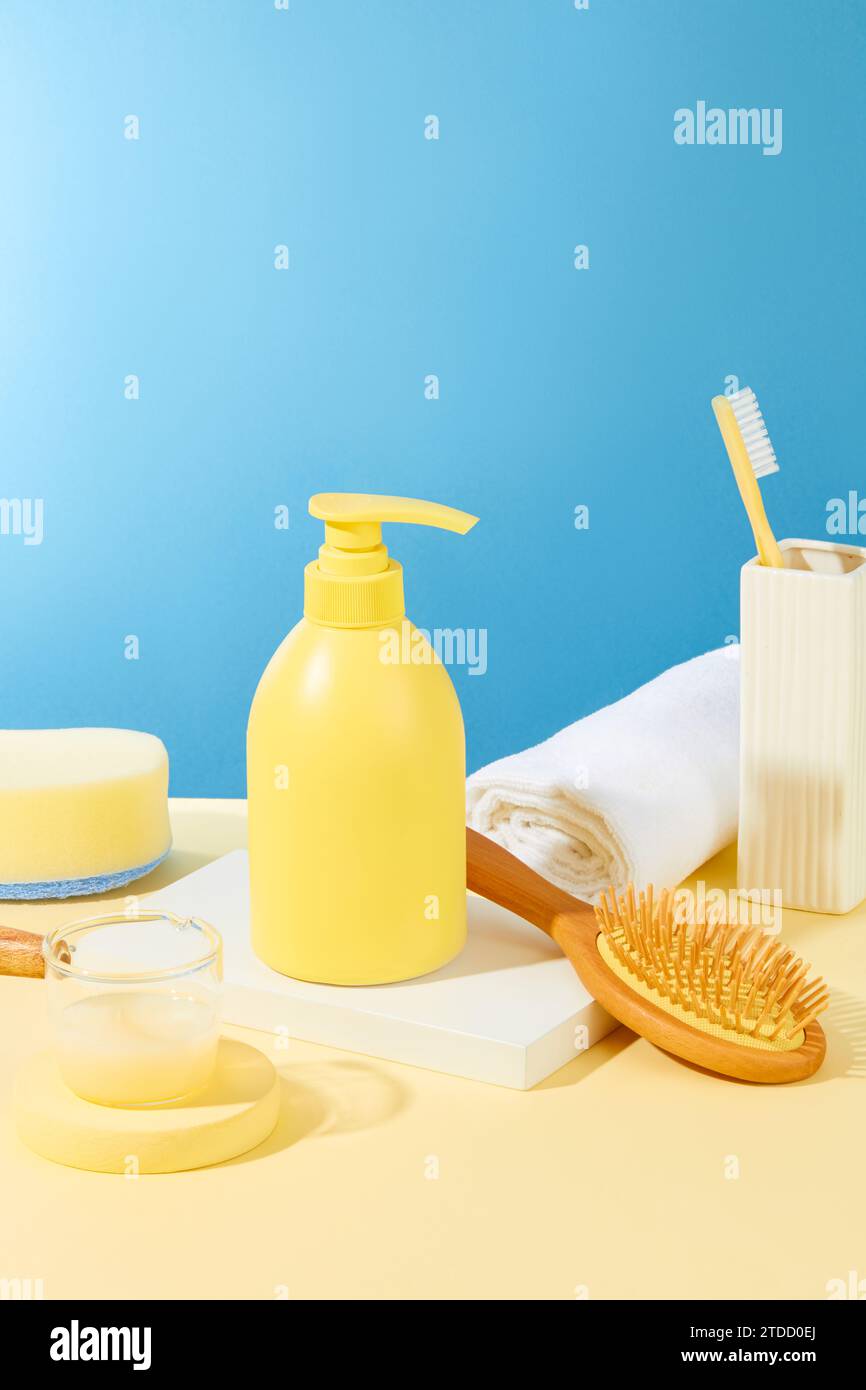 Une bouteille de gel douche est exposée sur un podium blanc avec un peigne démêlant et une serviette. Espace à l'intérieur de la salle de bain avec des produits d'hygiène personnelle. Banque D'Images