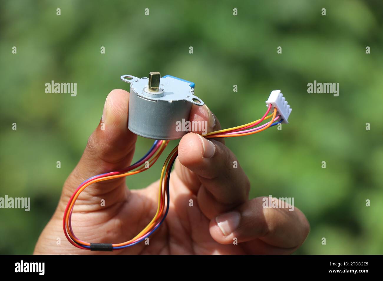 Moteur pas à pas qui fonctionne sur une alimentation cc isolé sur fond de nature tenu en main Banque D'Images