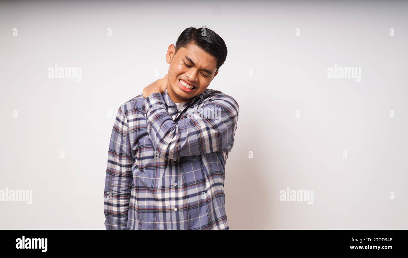 Geste d'un jeune homme asiatique souffrant de maux de dos sur fond blanc, photo studio Banque D'Images