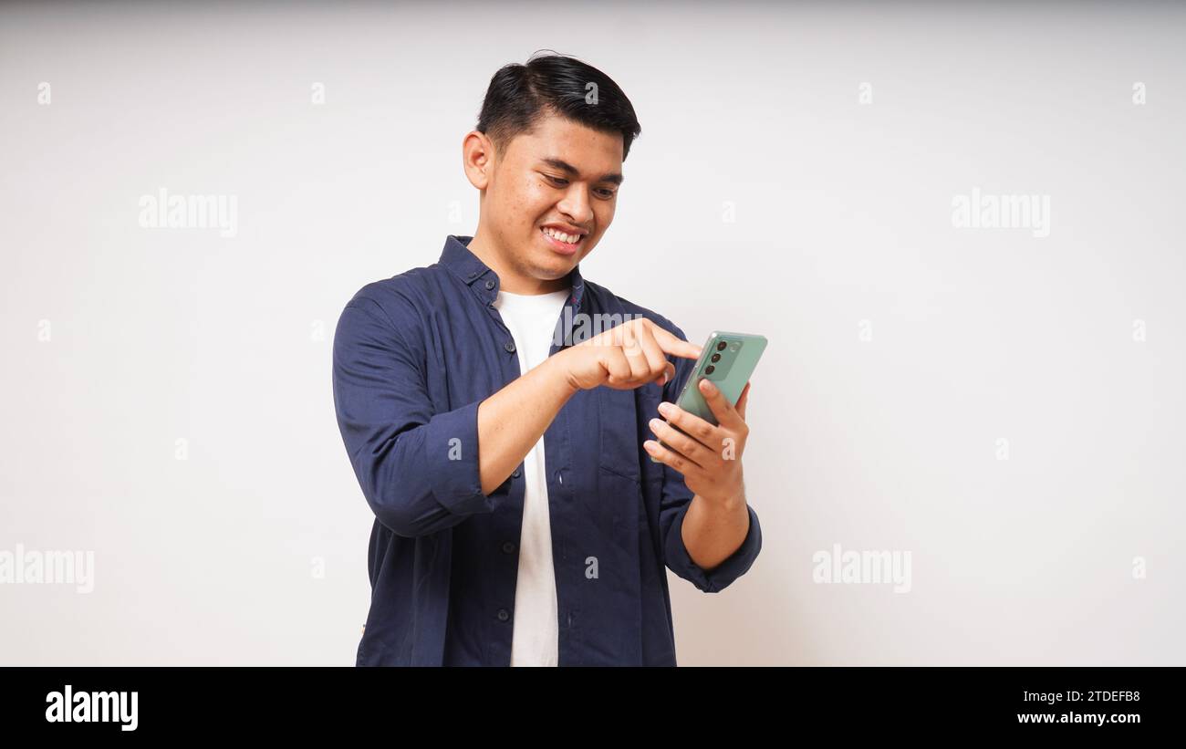 Jeune homme asiatique tenant un téléphone portable montrant une expression enthousiaste Banque D'Images