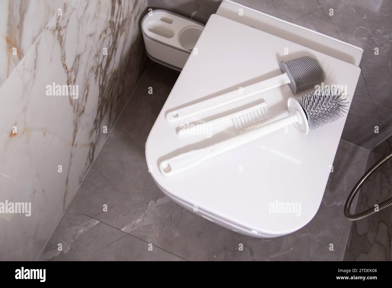 Les brosses en silicone pour nettoyer les toilettes reposent sur le couvercle des toilettes suspendues au mur. Le concept de soins et de nettoyage des toilettes de la saleté et des bactéries. G Banque D'Images