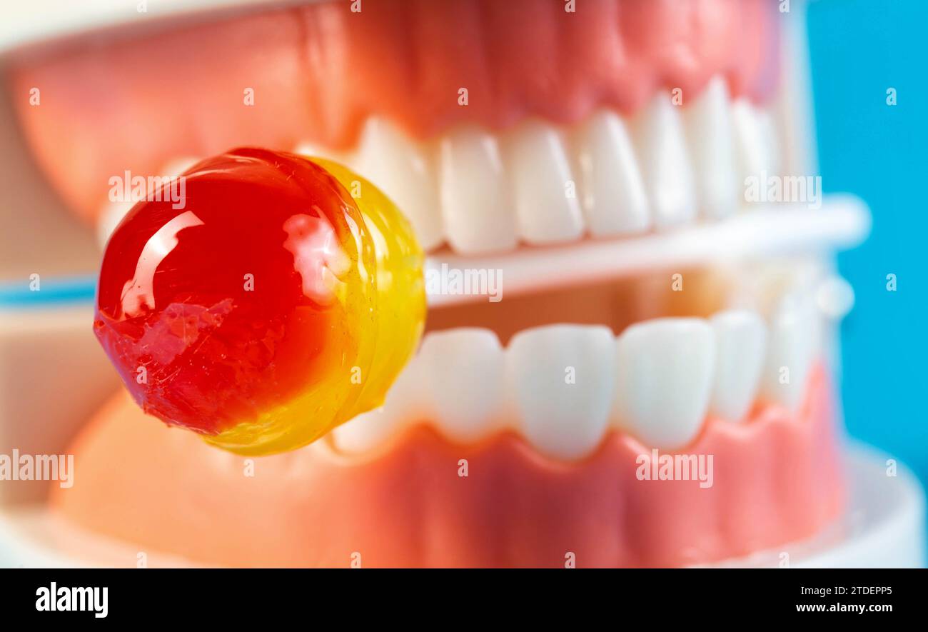 Bonbons sur un bâton dans une maquette de mâchoire de dent sur un fond bleu. Concept de l