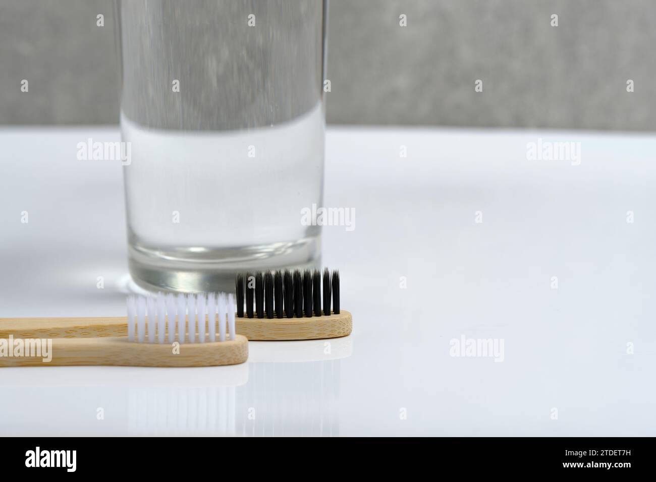 Eau en verre et deux brosses à dents en bois salle de bain sur fond blanc Banque D'Images