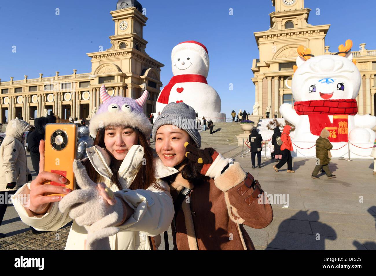 Harbin, province chinoise du Heilongjiang. 17 décembre 2023. Les touristes posent pour un selfie avec un bonhomme de neige géant à Harbin, dans la province du Heilongjiang, au nord-est de la Chine, le 17 décembre 2023. Le bonhomme de neige géant, d'environ 18 mètres de hauteur et fait avec quelque 2 000 mètres cubes de neige, devient un point de repère annuel de Harbin. Crédit : Liu Yang/Xinhua/Alamy Live News Banque D'Images
