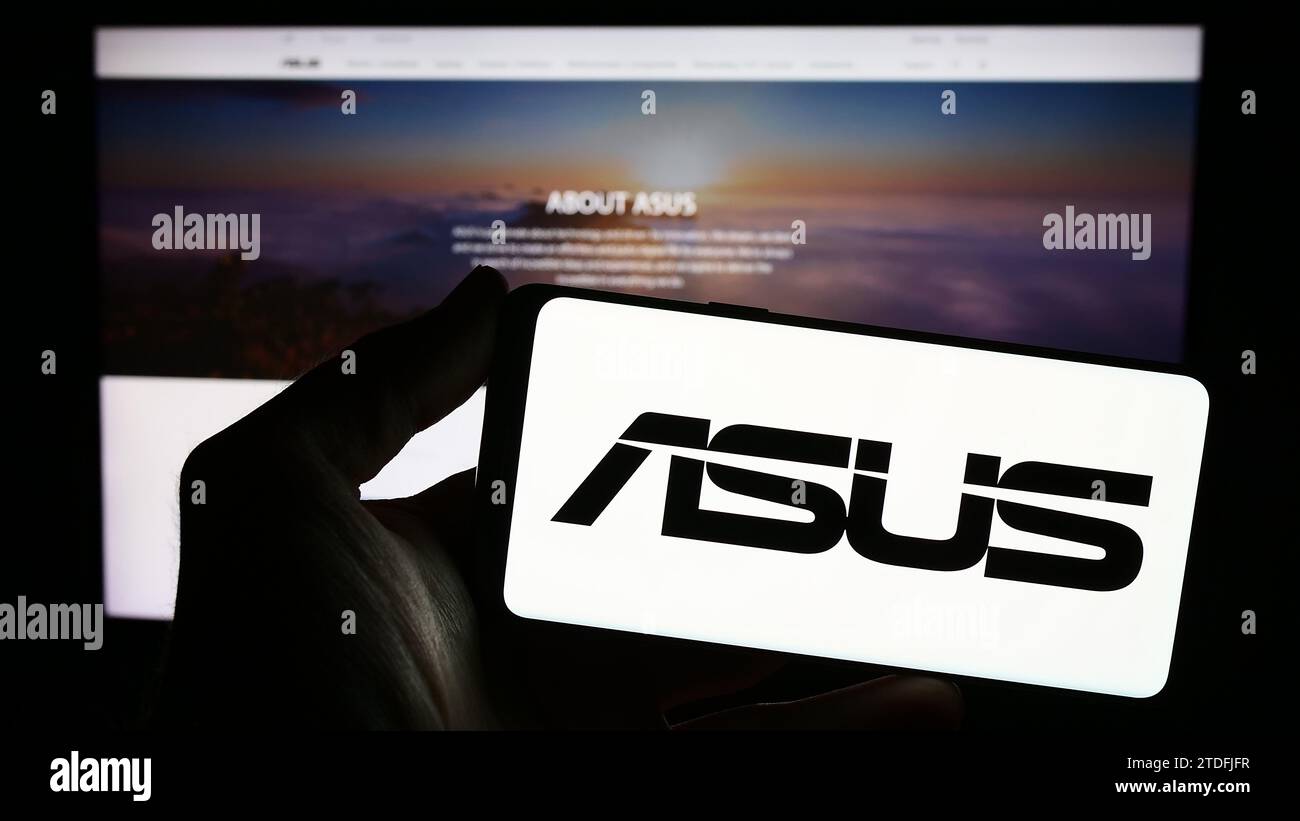 Personne détenant un smartphone avec le logo de la société taïwanaise ASUSTeK Computer Inc. (ASUS) devant le site Web. Concentrez-vous sur l'affichage du téléphone. Banque D'Images