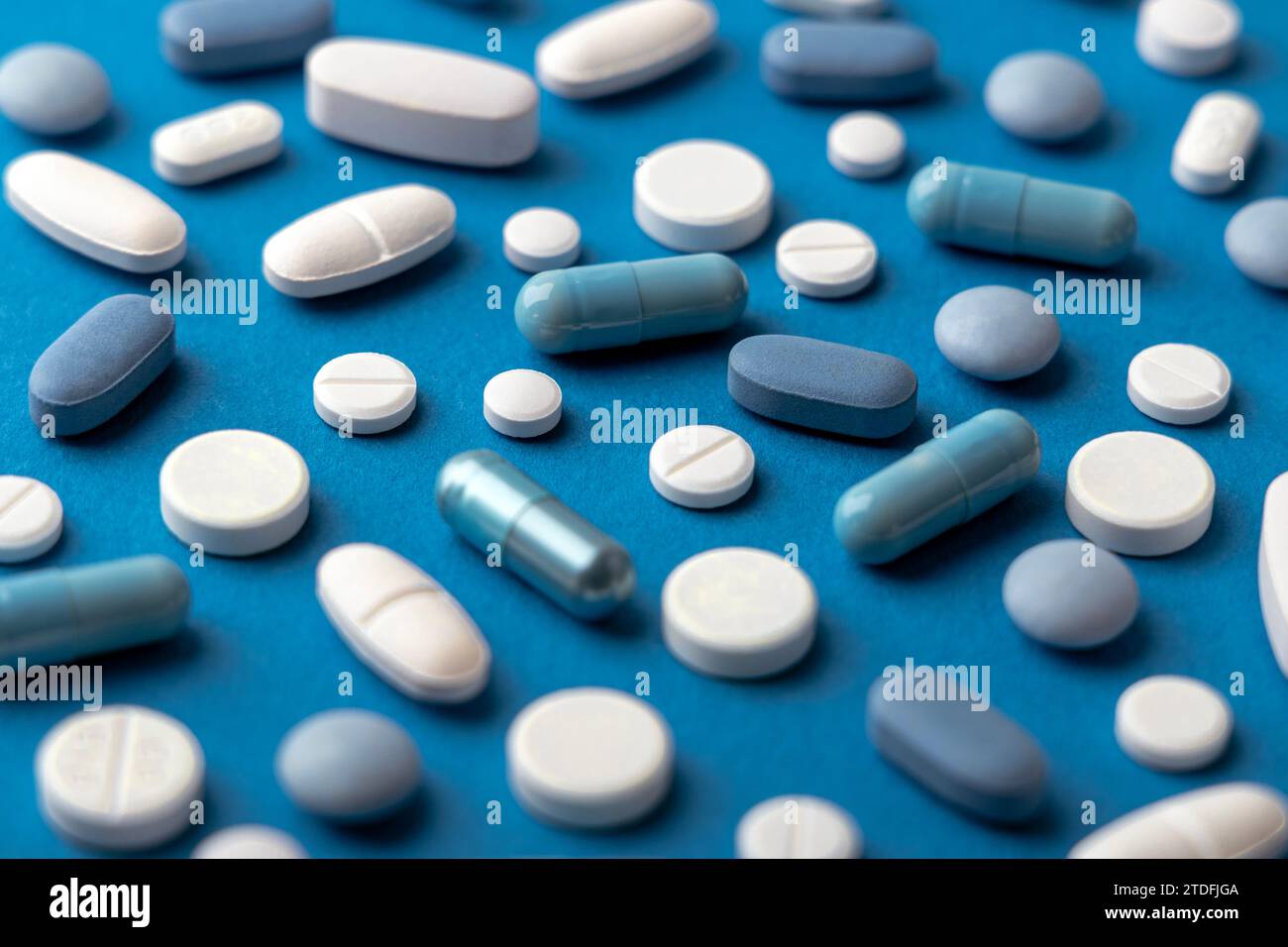Pilules et comprimés bleus et blancs sur fond bleu Banque D'Images