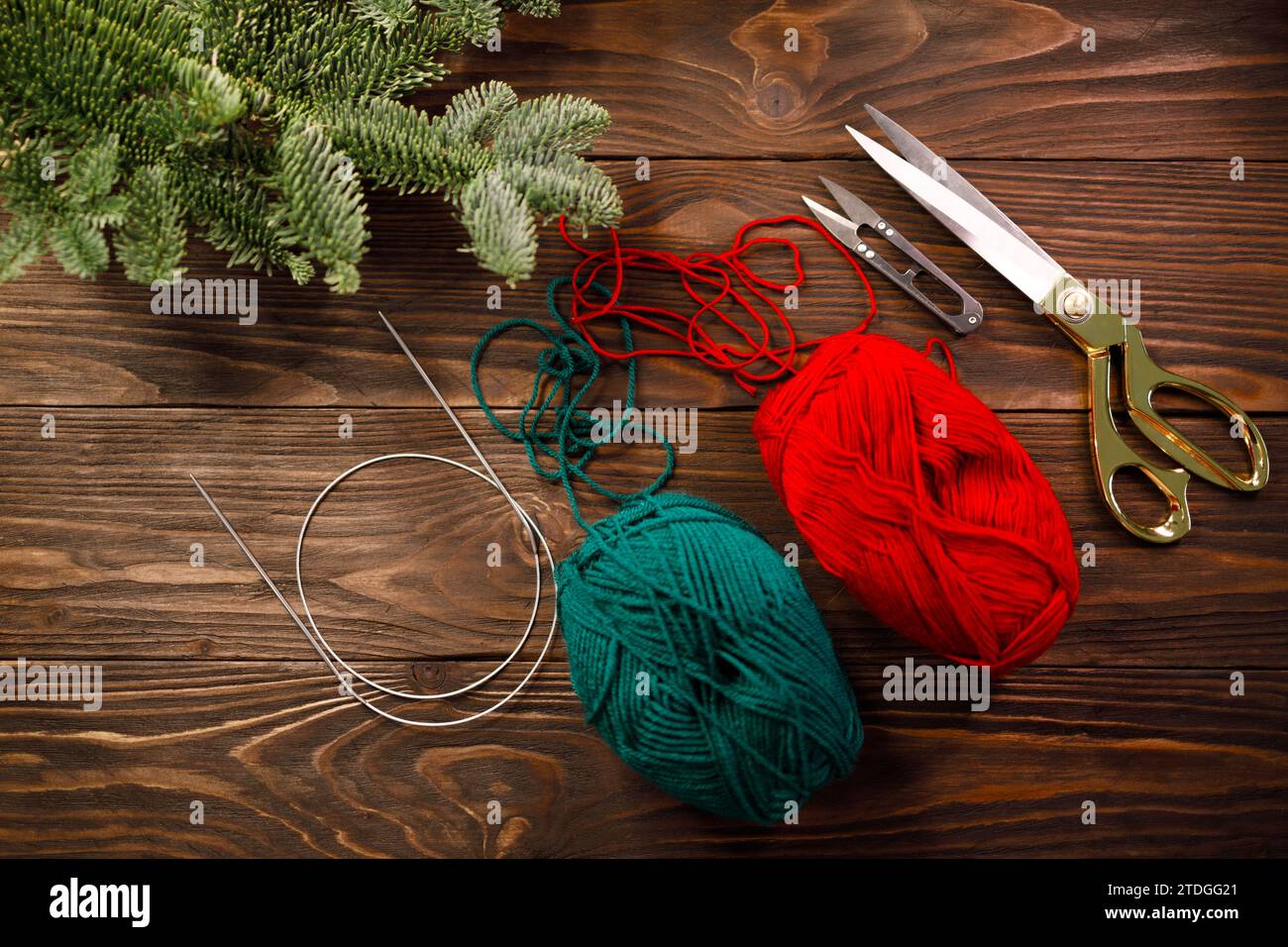 aiguilles à tricoter, fils et ciseaux sur une table en bois décorée de branches d'épicéa Banque D'Images