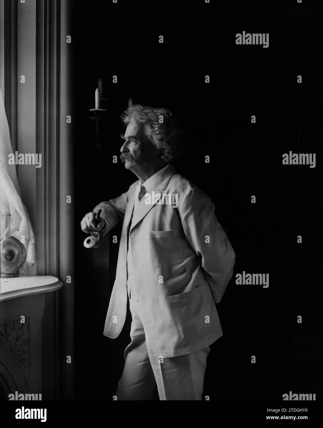 Mark Twain regardant par la fenêtre. Année : 1907. Par Underwood & Underwood. Banque D'Images