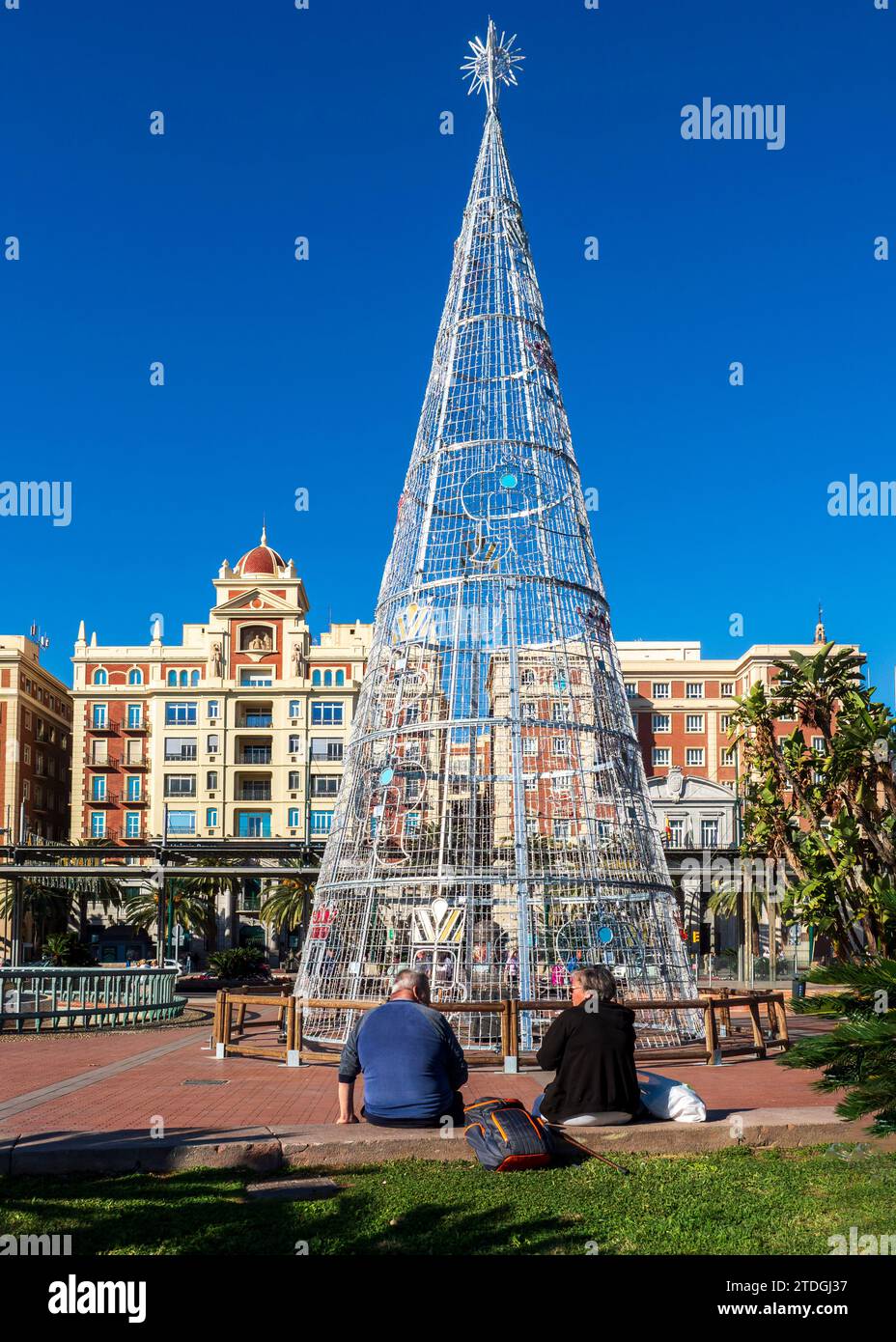 Malaga, Andalousie, Espagne. 11/06/2023. Couple de retraités devant le sapin de Noël sur la Plaza de la Marina à Malaga. Banque D'Images