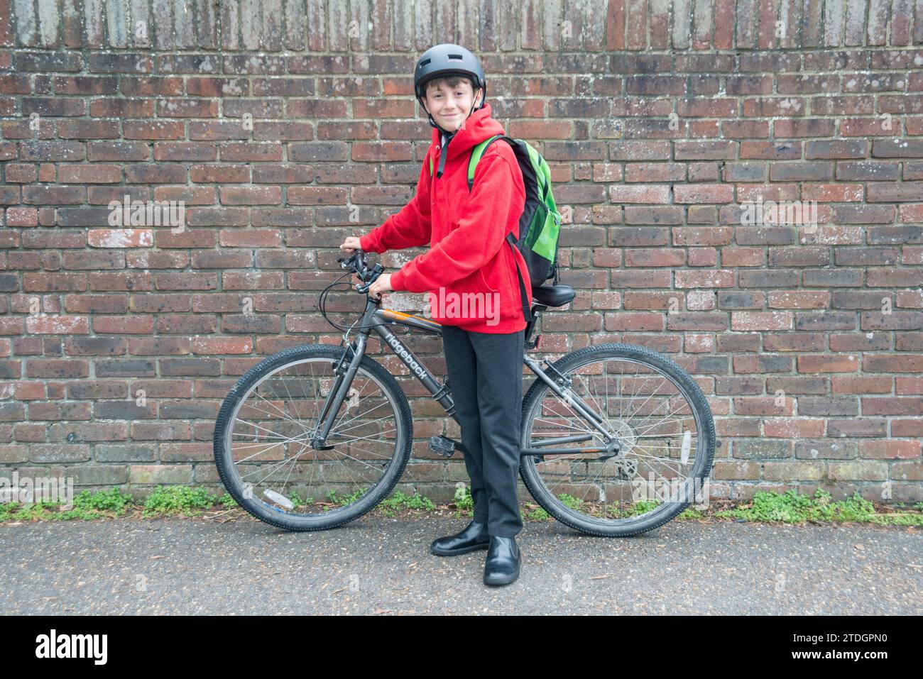 Un garçon avec son vélo prêt à voyager à l'école dans son uniforme Banque D'Images