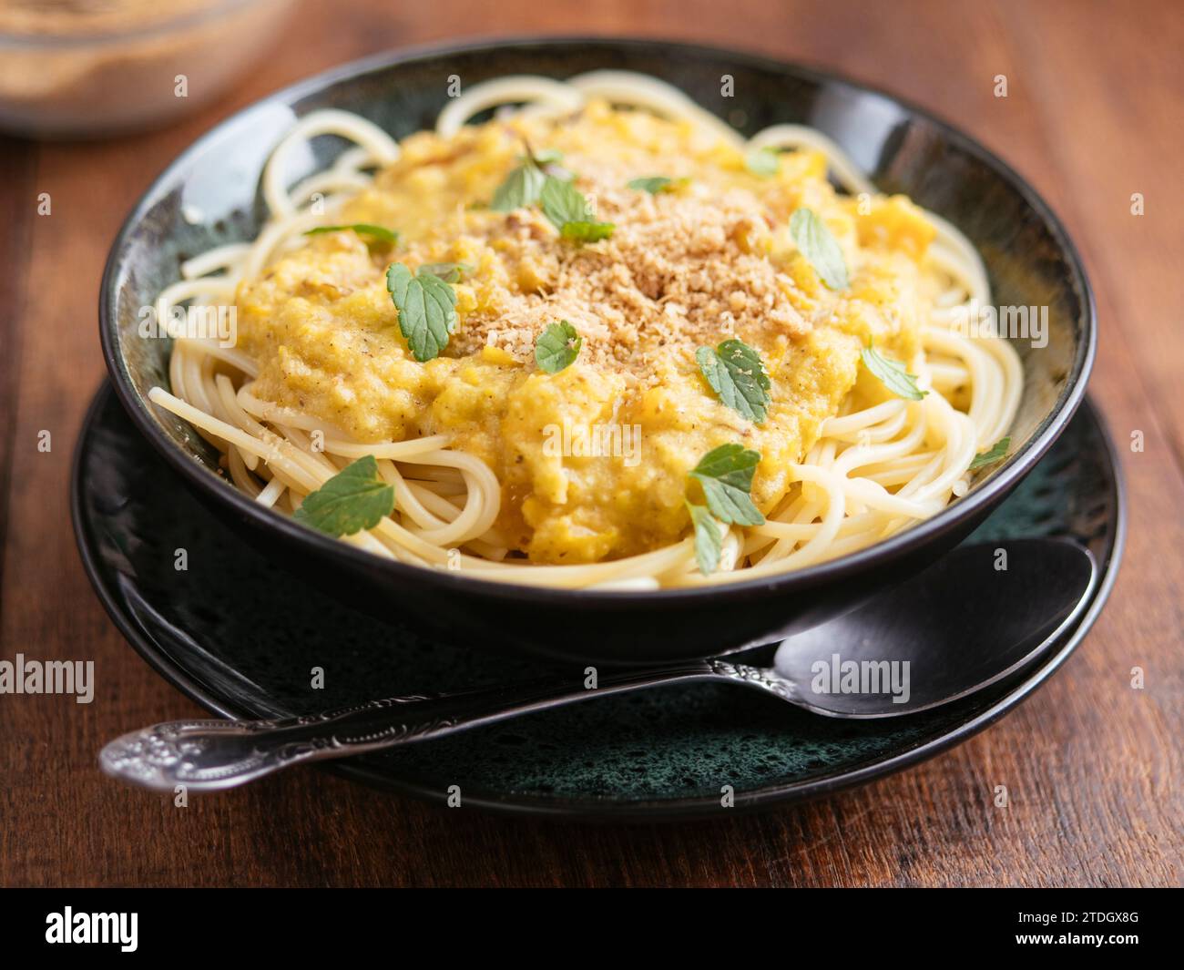 Bol avec spaghetti avec une sauce tomate verte et parmesan aux noix végétaliennes Banque D'Images