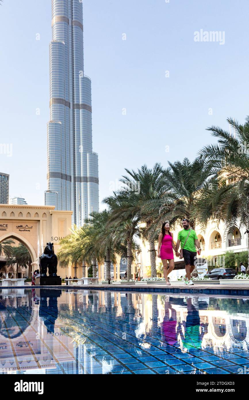Dubaï, Émirats arabes Unis. 18 décembre 2023. Un couple marche près d'une piscine en face de la tour Burj Khalifa par une chaude journée de décembre dans le centre de Dubaï. Crédit : Dominika Zarzycka/Alamy Live News Banque D'Images