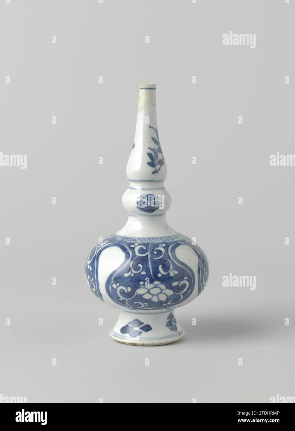 Arroseur d'eau de rose ou vase de bouteille avec des rouleaux floraux en réserve en lambrequins, anonyme, c. 1680 - c. 1720 gouttes d'eau de rose ou bouteille de pointe sur le haut, le pied d'étalement et deux épaississements dans le cou, peint en bleu sous glaçage. Sur le ventre une bande avec un motif en zigzag avec une bande avec une fleur de vignes sauvées en lambrequins dessous. Alternativement une fleur stylisée et une fenêtre. Sur le cou une bande avec des fleurs stylisées ; au-dessus de cette fleur branches. Bleu blanc. Porcelaine de Chine. glaçage. Cobalt (minéral) peinture / vitrification Rose gouttes d'eau ou pointe bouteille sur pied haut, étalant et deux thicke Banque D'Images