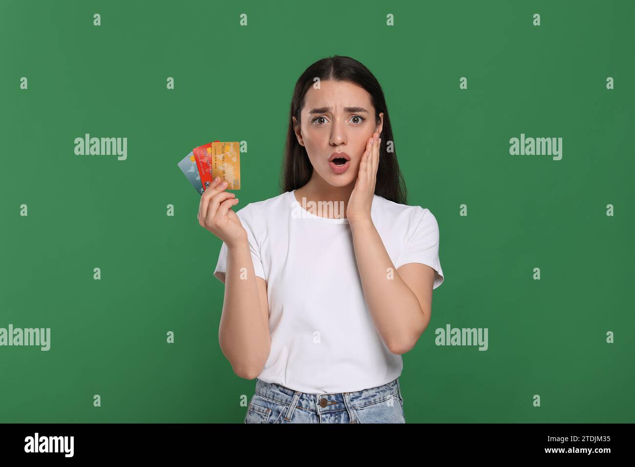Femme choquée avec carte de crédit sur fond vert. Problème de dette Banque D'Images