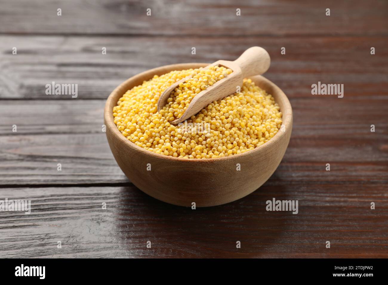 Gruaux de millet dans un bol et pelle sur une table en bois Banque D'Images