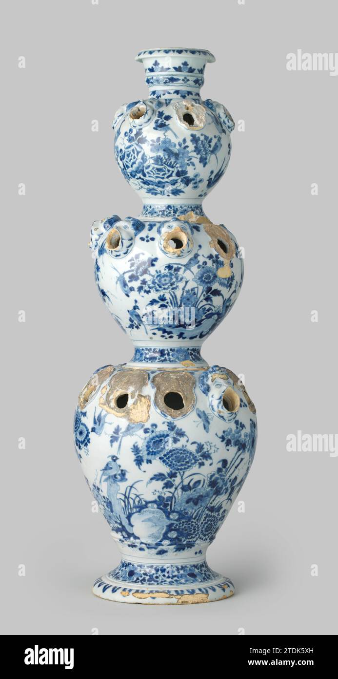 Porte-fleurs, anonyme, c. 1680 - c. 1700 Bloemhouder de faïence peinte en bleu. Le vase se compose de trois vases les uns sur les autres, dont le fond est grand et canope et le dessus petit et sphérique. Chaque vase a un pied rond. Sur les épaules de chaque vase, des têtes d'ange soufflantes étaient en relief, de la bouche desquelles sont présents des poignets. Ces taches sont décomposées pour les deux vases. Les vases sont chacun peints avec des fleurs sur et près des rochers et des oiseaux (y compris des paons). Faïence Delft. glaçure d'étain. Bloemhouder de faïence peinte en bleu. Le vase se compose de trois vases les uns sur les autres, Banque D'Images