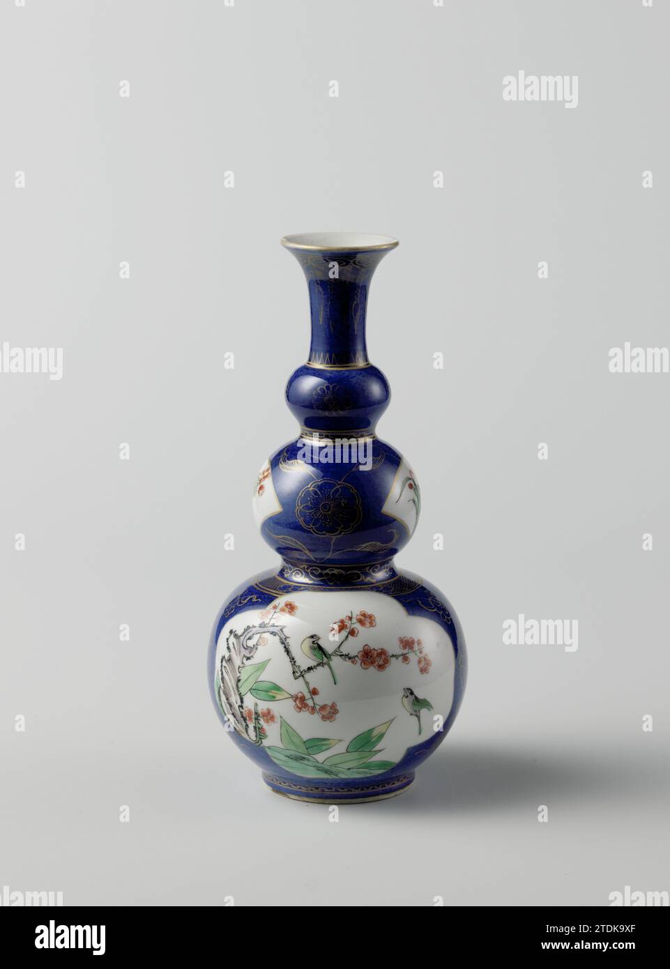 Vase en forme de bouteille en forme de triple gourde avec poudre bleu et sprays de fleurs et oiseaux, anonyme, c. 1700 - c. 1724 vase en forme de bouteille (morceau de leçons) de porcelaine avec trois couches, peint en bleu glacé sous-jacent et sur le glaçage rouge, vert, jaune, aubergine, noir et or. La bouteille est recouverte de poudré bleu (bleu poudré) avec deux grands cours lobés remplis de Prunus ou Lotus avec des oiseaux ; deux compartiments en forme d'éventail avec des branches de fleurs ; entre les cours, des vaisseaux floraux en or, entre les épaississements, des pneus décoratifs avec des motifs géométriques, des vignes fleuries et motif Ruyi en or. Une puce dedans Banque D'Images