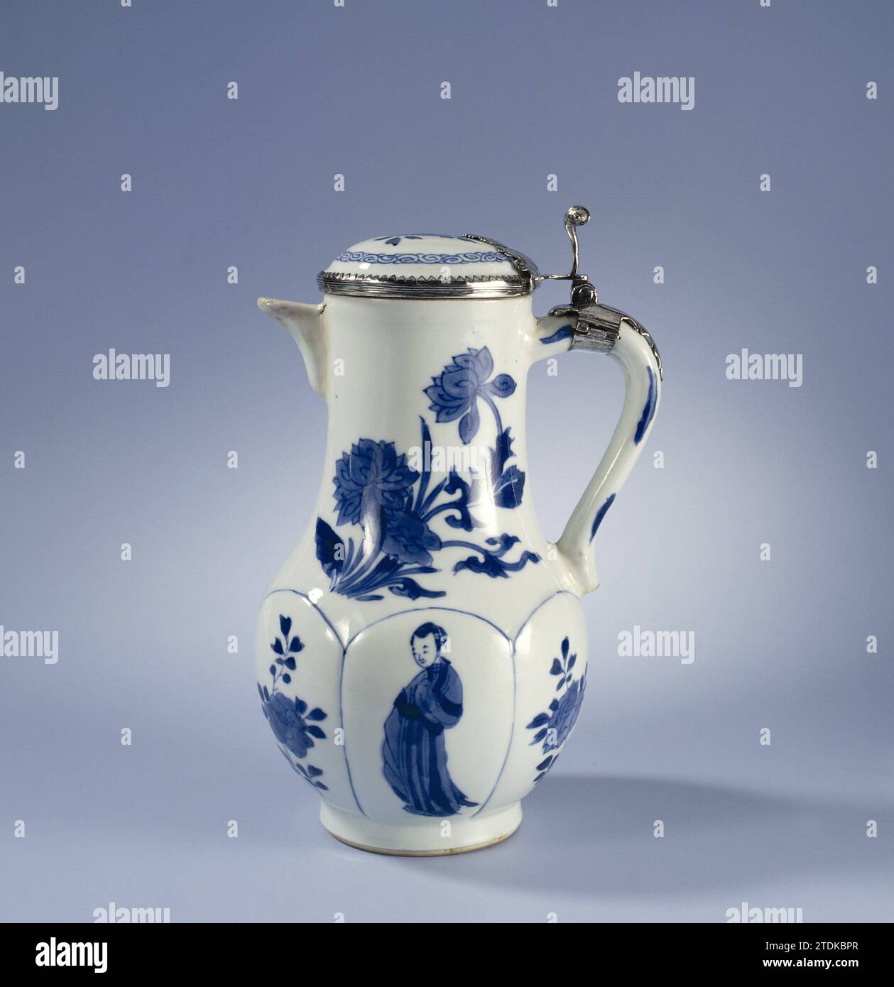 Pot à lait couvert avec des plantes de lotus, des sprays de fleurs et des femmes, anonyme, c. 1700 - c. 1724 pot à lait en porcelaine avec corps en forme de poire, couvercle et petit bec triangulaire, peint en bleu sous-laque. Le ventre est divisé en six compartiments avec une branche de fleur et une femme (longues lijs) alternativement. Sur le cou large deux fois une plante de lotus en fleurs. Sur le couvercle une branche de fleur et une bande avec travail en spirale. Marqué sur le bas avec 'yù', Jade. Cadre argenté contemporain. Bleu blanc. Porcelaine de Chine. Glaçage. Cobalt (minéral). Cadre : argent (métal) peinture / vitrification pot à lait en porcelaine avec forme de poire Banque D'Images