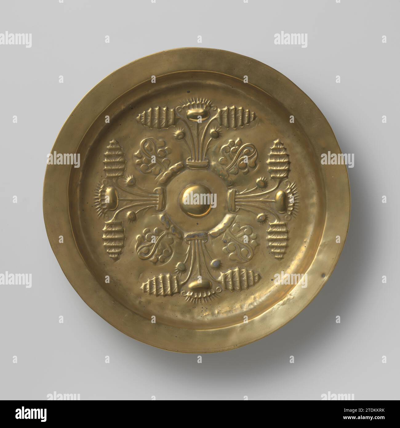 Plat décoré avec quatre fleurs de chardon, anonyme, 1450 - 1500 dans le plat du plat, qui a le point central au milieu, sont poinçonnés à l'aide de formes de timbre: une partie centrale haute ronde, entourée d'une plante placée dans un récipient composé d'une fleur de chardon, de deux feuilles et de deux boutons floraux, et d'une forme de feuille stylisée sur une zone de bordure. Ces motifs ont été répétés quatre fois. Le long du bord de la cuvette est un anneau parallèle rainuré et percé d'un trou. Plus tard, des points d'usure avec de l'étain ou du plomb ont été récupérés à l'arrière et un anneau de suspension a été soudé. Neurenberg (peut-être) laiton Banque D'Images