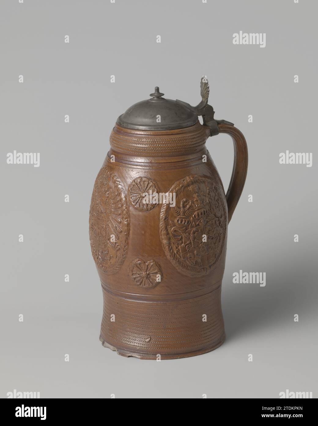 Tankard aux armoiries de Saxe-Pologne, anonyme, c. 1700 - c. 1730 tasse à bière en grès sur un pied légèrement écarté avec un corps en forme d'oeuf et une oreille en forme de C. Recouvert d'un engobe brun. Profils sous le bord et au-dessus du pied. Médaillons imprimés et imposés sur le ventre en relief. Les trois grands avec : l'arme nationale avec un bouclier et deux fois la double arme de Saxe-pôles. Entre quatre petits médaillons avec rosettes. Au-dessus du pied et en dessous du bord une bande avec des lignes ondulées. Attaché à l'oreille un cadre en étain avec couvercle. Le couvercle a un bouton et un thum en forme de coquille Banque D'Images