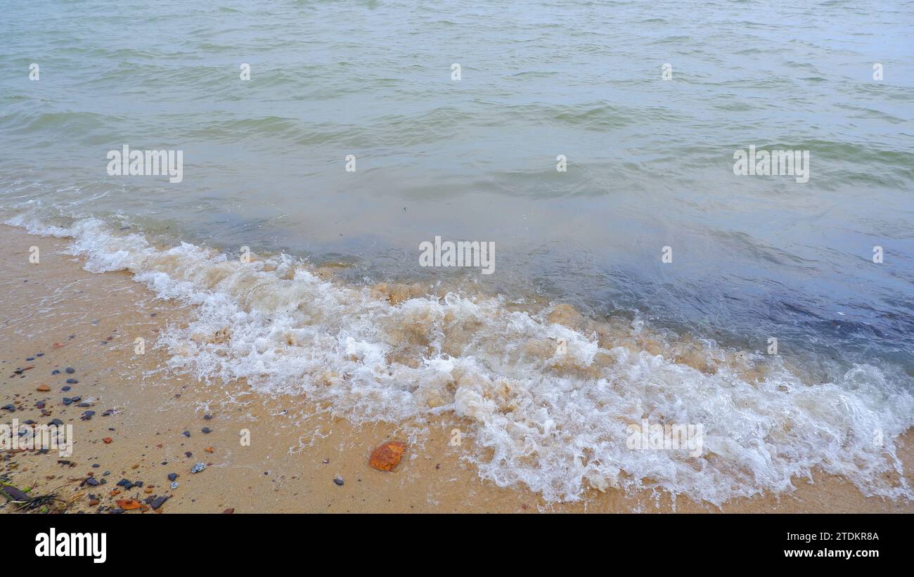 L'écume des vagues de la mer se brise sur le rivage de Tanjung Anda, Indonésie Banque D'Images