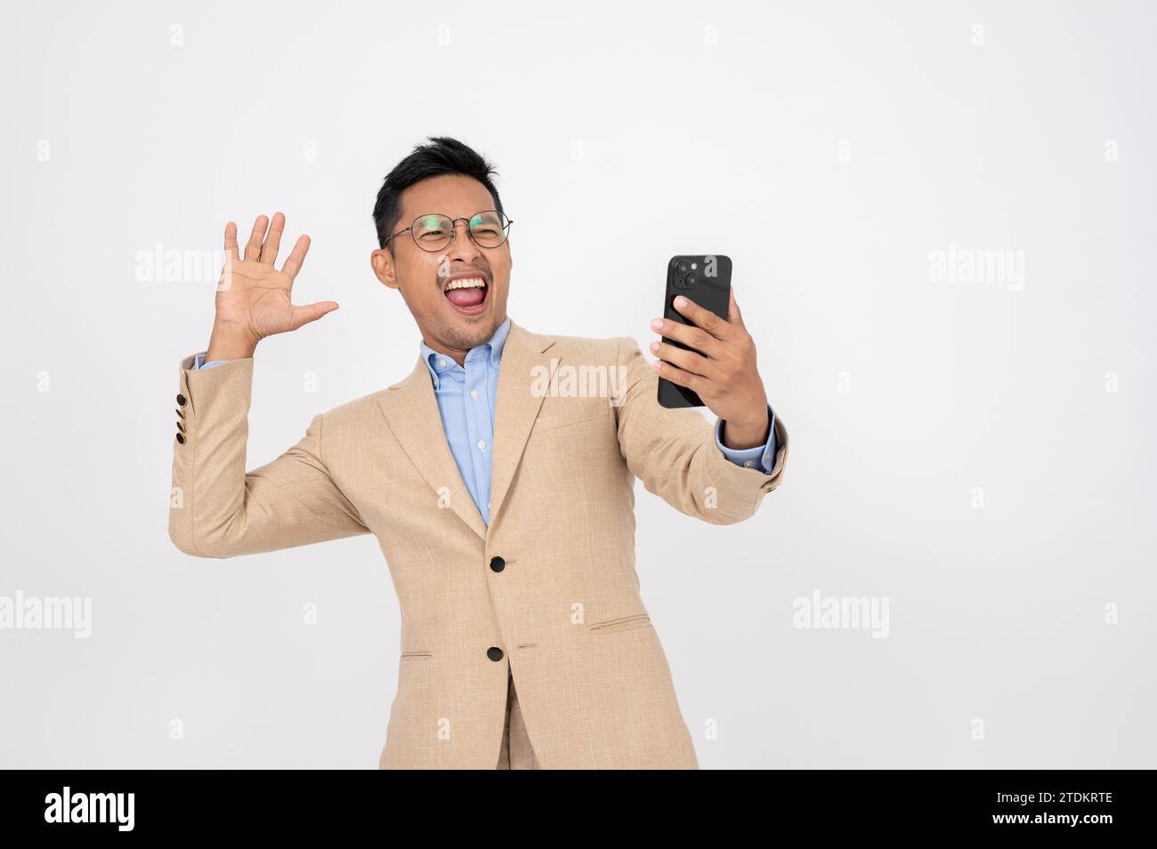Un homme d'affaires asiatique choqué et excité regarde l'écran de son téléphone avec un visage surprenant tout en se tenant debout sur un fond blanc isolé. offre spéciale Banque D'Images