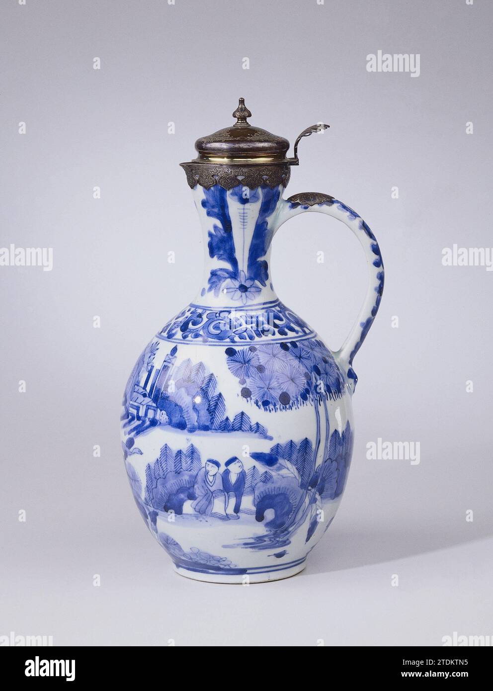 Aiguière avec des figures dans un paysage, rouleaux floraux, motif tulipe et monture argentée, anonyme, c. 1650 - c. 1699 cruche en porcelaine avec corps sphérique, oreille en forme de C et petit bec triangulaire dans le bord. Peint en bleu sous-couche. Sur le ventre une performance continue avec des gens dans un paysage avec de la roche, des arbres, des plantes, un oiseau volant et des maisons. Une personne a un drapeau en main. Sur l'épaule un lien avec des branches. L'épaule avec deux fois un motif tulipe. Rang sur l'oreille. Autour du bord, un cadre argenté postérieur avec couvercle, lettre annuelle Z (1859). Arita, Blauw-Wit. Porcelaine du Japon. glaçage. cobalt (minera Banque D'Images