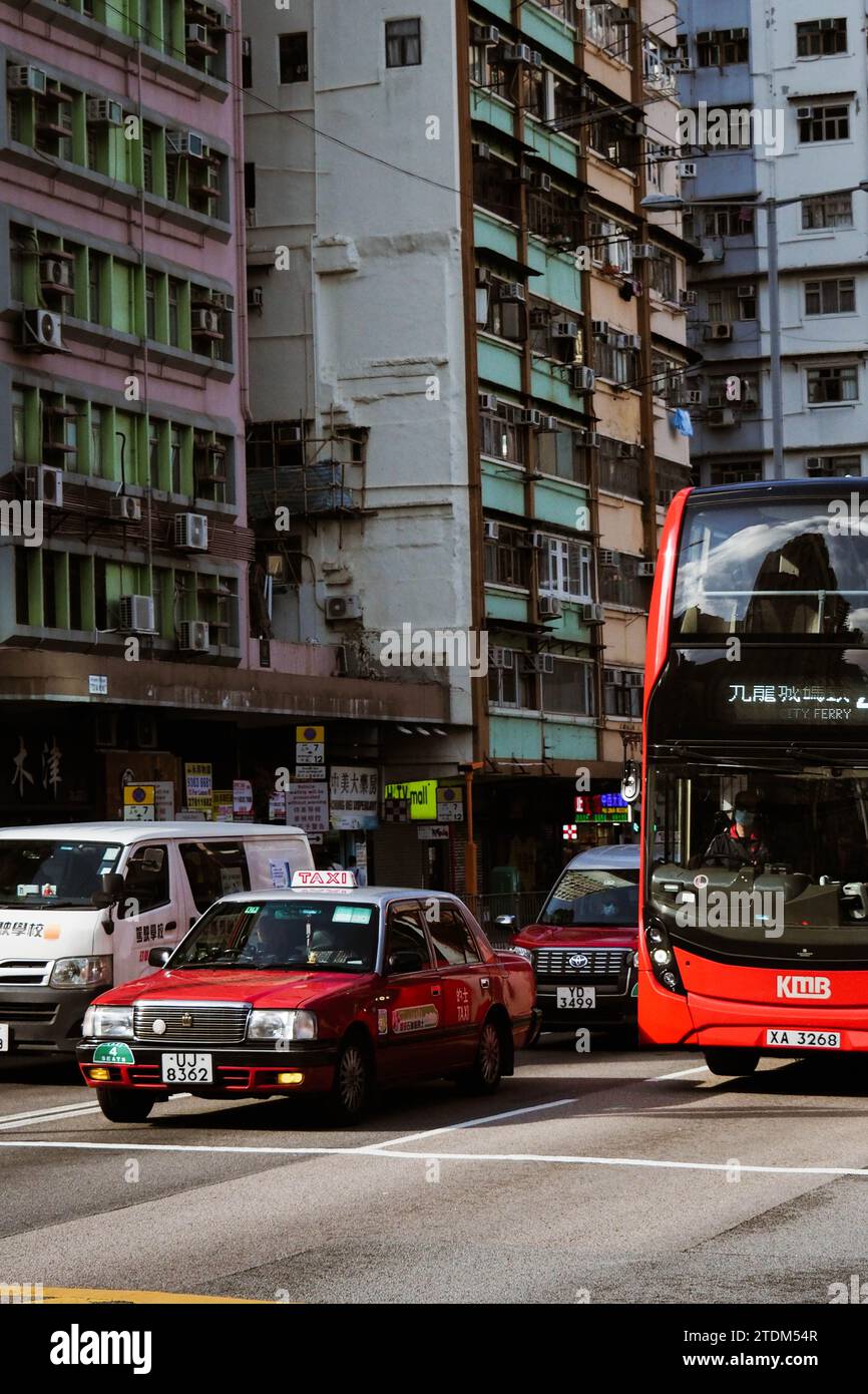 Un taxi et un bus de Hong Kong - entre autres voitures - attendent à un feu de circulation à une intersection animée à Hong Kong. Banque D'Images