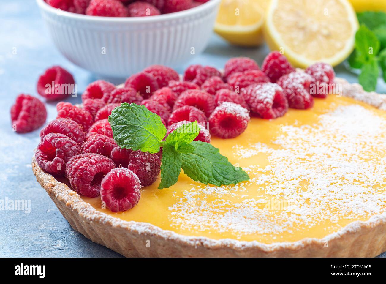 Tarte au citron maison, garnie de framboises fraîches, sucre glace et menthe, gros plan horizontal Banque D'Images