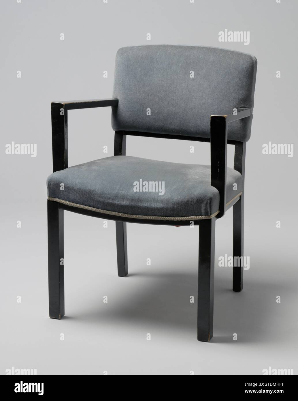 Fauteuil avec accoudoirs angulaires et recouvert de Trijp bleu, Jacobus Fernandus Adolphus Semey, 1933 fauteuil en bois laqué noir reposant sur quatre pieds carrés. Les pattes avant sont droites et les pattes arrière sont légèrement pliées et continuent dans les styles arrière. La séance se déroule en quatre lignes dont les deux règles latérales sont justes et la règle avant et arrière pliée. La référence du dossier est également pliée. Du centre du dossier, les accoudoirs angulaires plats partent qui sont à l'avant, non alignés avec les jambes avant, sur des jambes plates qui sont en partie fixées au siège et en partie. Les deux handrai Banque D'Images