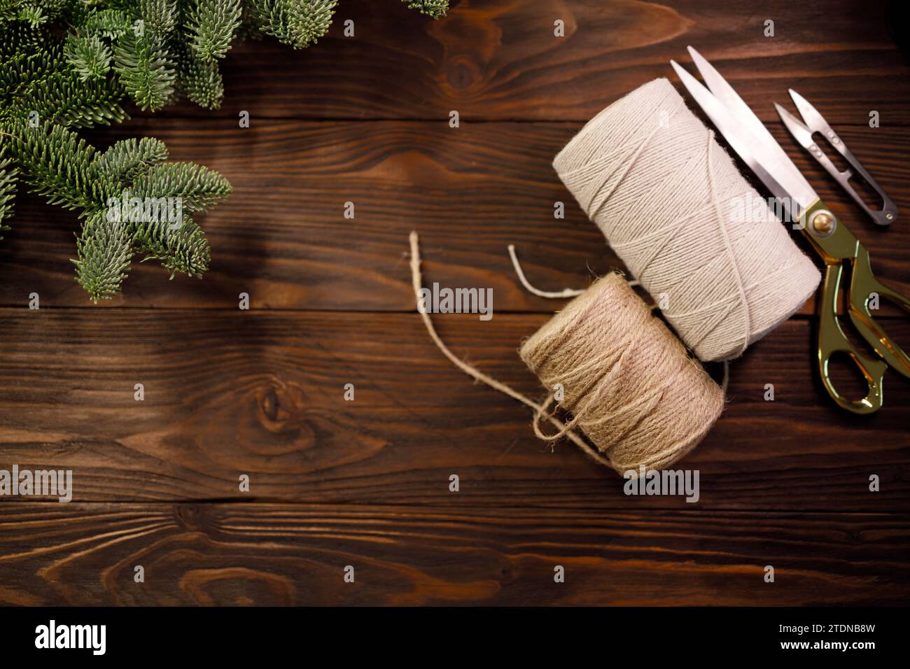 ciseaux, corde de coton torsadée et corde de toile de jute sur une table en bois décorée de branches d'épicéa Banque D'Images