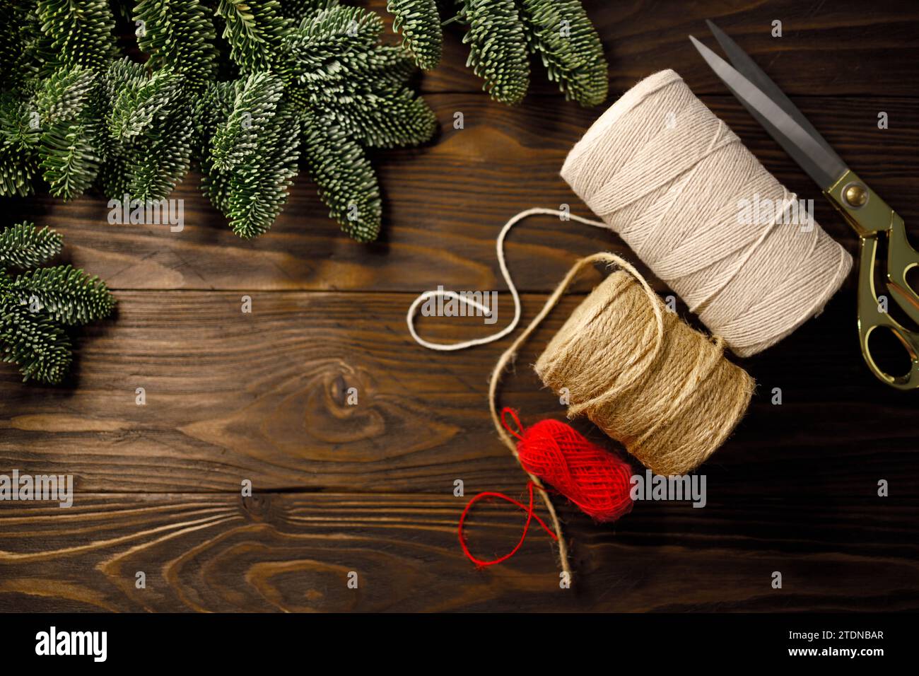 ciseaux, corde de coton torsadée et corde de toile de jute sur une table en bois décorée de branches d'épicéa Banque D'Images