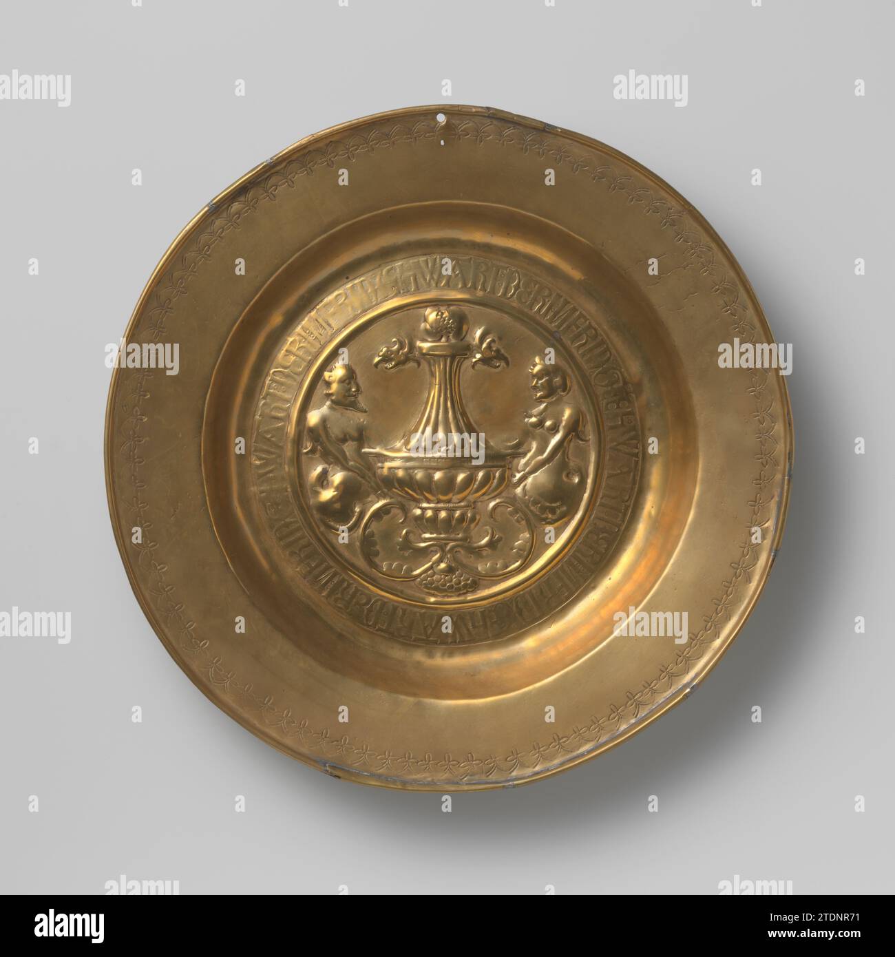 Plat avec Renaissancevaas arrêté par Hermen, Anonyme, 1500 - 1550 dans le plat du plat, qui a le point central au milieu, sont poinçonnés à l'aide de formes de timbre: un Renaissancevaas décoré de grognements avec un couvercle, qui est arrêté par un mâle et une femelle Herm, ainsi que l'inscription appliquée sur fond ombragé quatre fois Der in Frid hwahrt. En outre, le long du bord, qui a été battu pour le fil de fer, un ornement poinçonné de fleurs croisées a été appliqué. L'anneau de suspension à l'arrière et le trou dans le bord ont été installés plus tard. Le point central est devenu un petit openi Banque D'Images