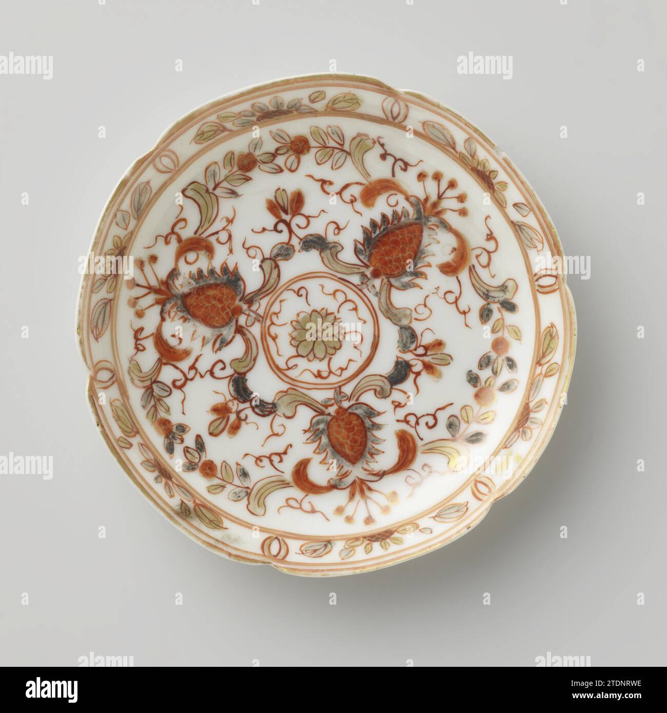 Soucoupe à rouleaux et fleurs stylisées, anonyme, c. 1700 - c. 1724 plat en porcelaine avec six bords lobés, peint sur la glaçure en rouge, noir et or. Sur le plat un médaillon avec fleur stylisée et terres ; autour du médaillon une bande avec des fleurs stylisées reliées, des branches et des tifles ; le bord avec six cartouches avec branche de fleur. Une puce dans le bord du plat. Lait et sang. Porcelaine de Chine. glaçage. Or (métal) peinture / dorure / vitrification plat en porcelaine avec six fois le bord lobé, peint sur la glaçure en rouge, noir et or. Sur le plat un médaillon avec fleur stylisée an Banque D'Images