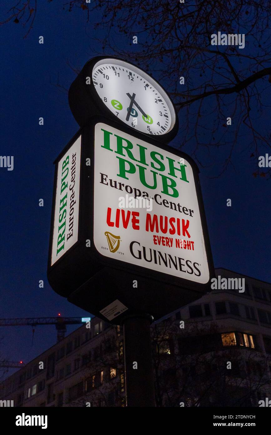Panneau de bar avec une horloge, pour un pub irlandais servant Guinness à Europa Center, Berlin, Allemagne, illuminé dans les sombres soirées d'hiver. Banque D'Images
