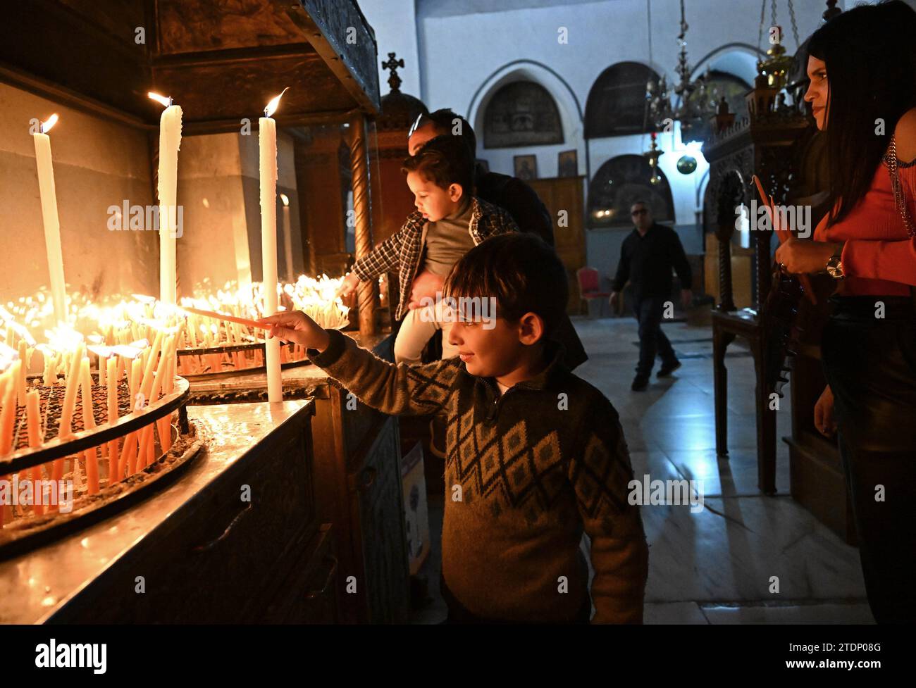 Bethléem, Cisjordanie. 17 décembre 2023. Un garçon chrétien palestinien allume une bougie dans l’église de la Nativité, que l’on croit être le site de la naissance de Jésus, dans la ville biblique de Bethléem, Cisjordanie, le dimanche 17 décembre 2023. L’église, normalement remplie de touristes, est vide depuis octobre 8, le lendemain de l’attaque du Hamas contre Israël et du début de la guerre dans la bande de Gaza. Les dirigeants chrétiens ont annulé l’érection du sapin de Noël sur la place du Manager, les joyeuses décorations de rue et les célébrations en solidarité avec les Palestiniens de Gaza. Photo de Debbie Hill/ crédit : UPI/Alamy Live News Banque D'Images