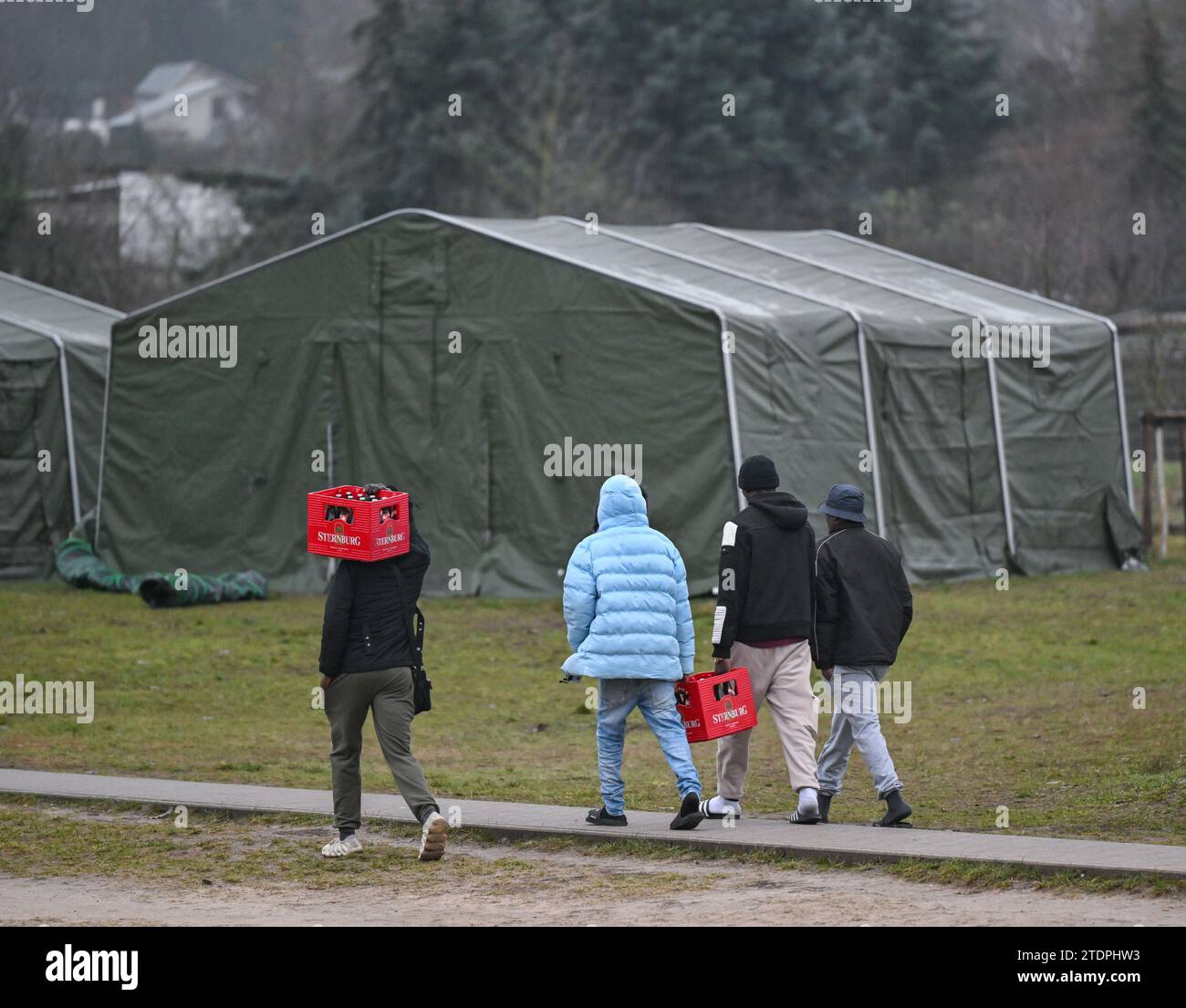 14 décembre 2023, Brandebourg, Eisenhüttenstadt : les migrants transportent des caisses de bière à leur logement sur le terrain du Centre central d'accueil pour demandeurs d'asile de Brandebourg (ZABH) à Eisenhüttenstadt. Photo : Patrick Pleul/dpa Banque D'Images