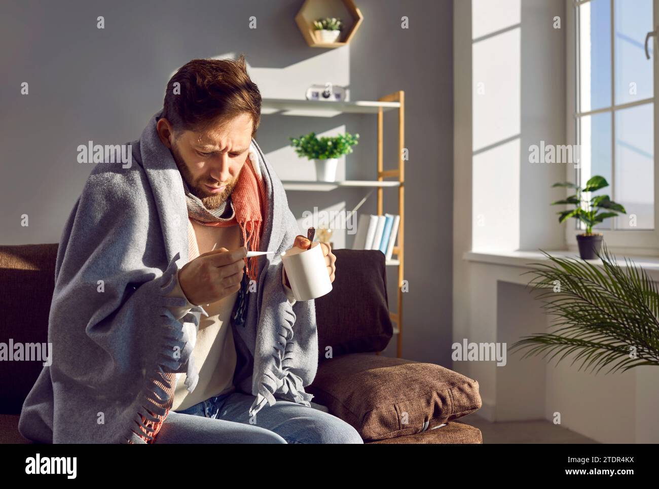 Le jeune homme regarde le thermomètre qui indique une température élevée. Banque D'Images