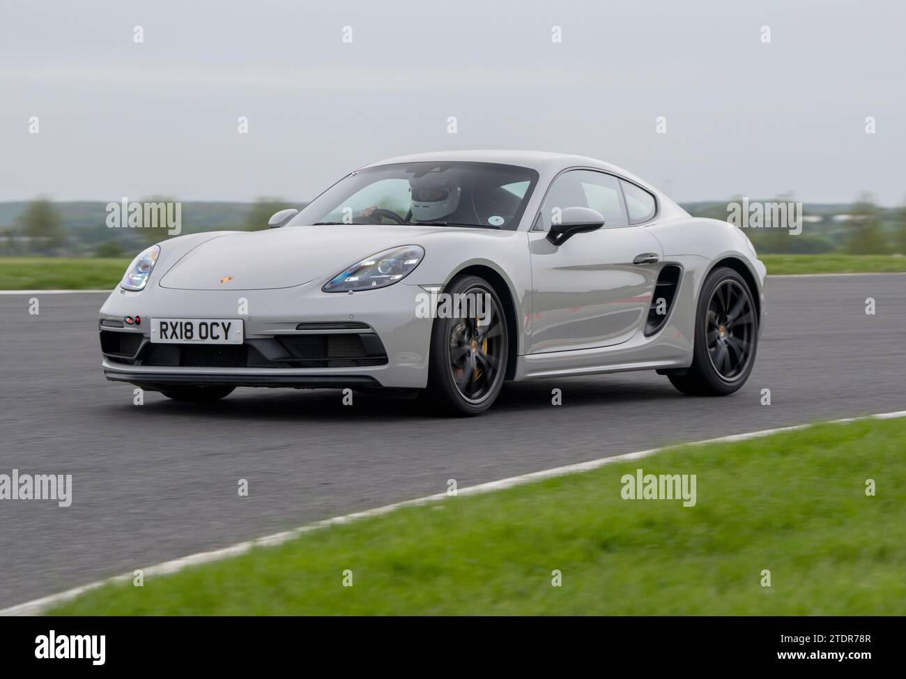Porsche Cayman conduisant rapidement sur piste lors d'une course de jour Banque D'Images