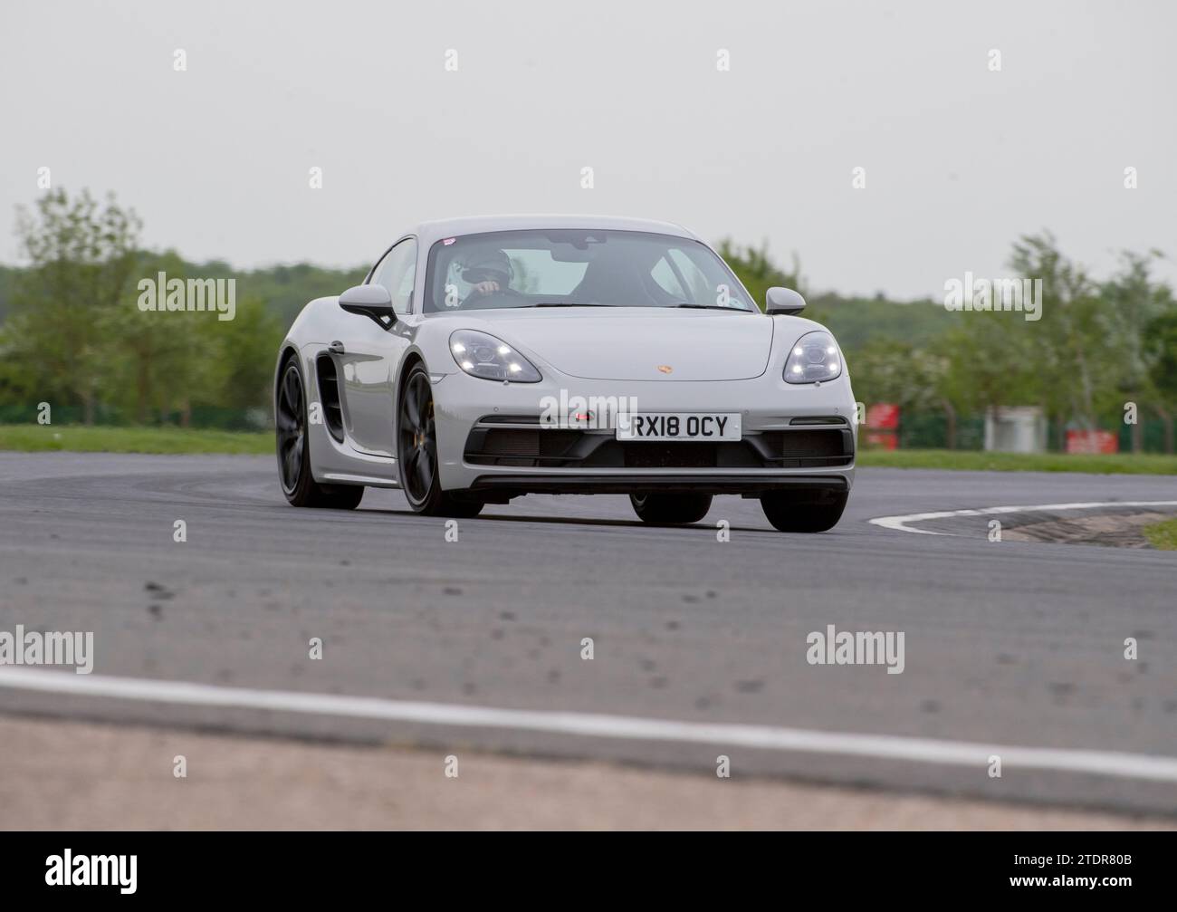 Porsche Cayman conduisant rapidement sur piste lors d'une course de jour Banque D'Images