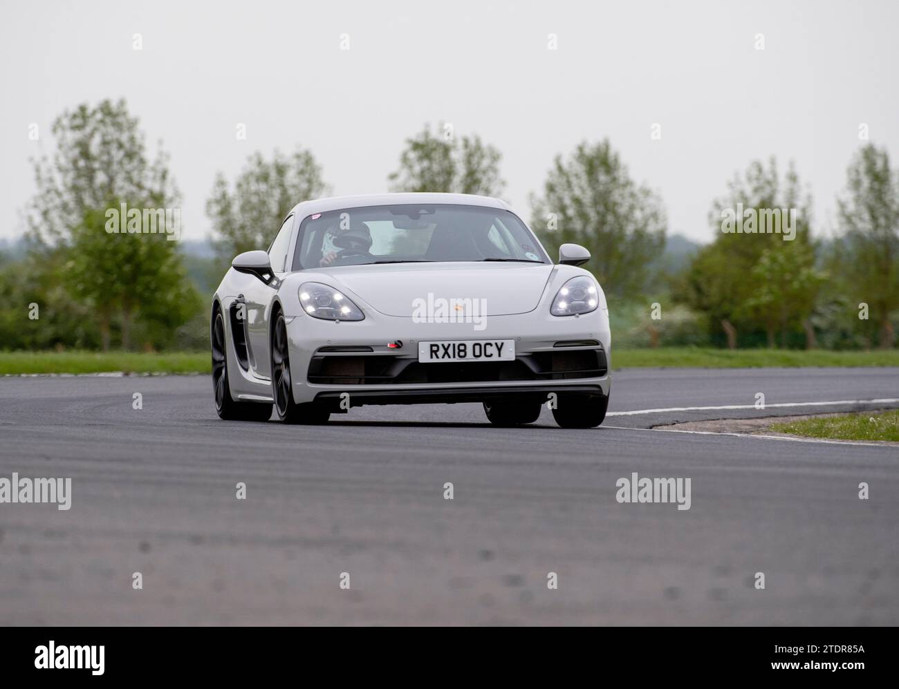 Porsche Cayman conduisant rapidement sur piste lors d'une course de jour Banque D'Images